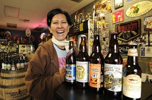 Arlene Nunez, owner of By the Bottle, shows off a selection of fall beers at her store. Pumpkin ales, fresh hop and oktoberfest beers are all brewed with autumn flavors in mind. (Photo by Troy Wayrynen of The Columbian)