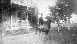 The wife of General Alfred Sully mounted sidesaddle on the lawn in front of the Grant House porch at the Vancouver Barracks.