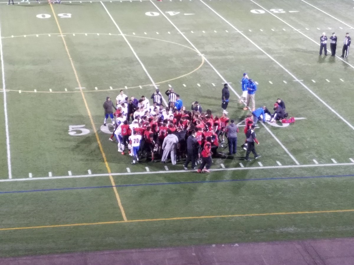 Fort Vancouver football players kneel with Benson players after a Benson player suffered a significant leg injury