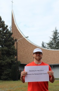 The Rev. Brooks Berndt stands in front of the First Congregational Church of Christ in Vancouver with a sign promoting the "Running for Our Lives" marathon.